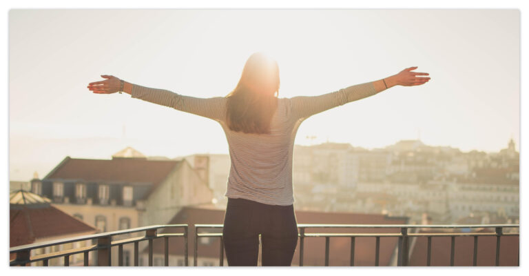 a woman standing on a balcony with her arms outstretched